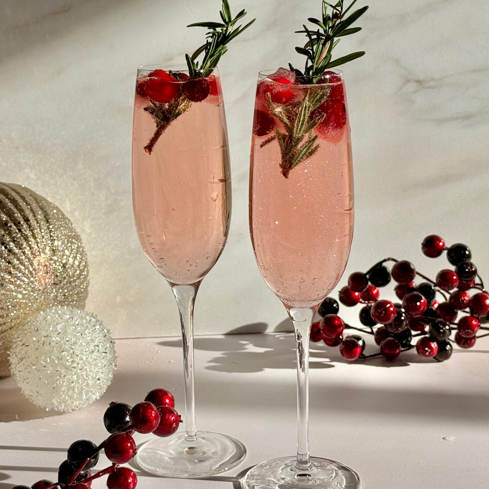 Two cranberry mimosa holiday drinks in champagne flutes