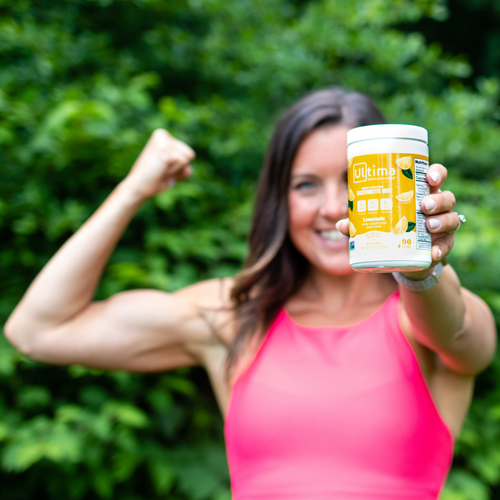 woman holding a canister of Ultima Lemonade electrolyte mix