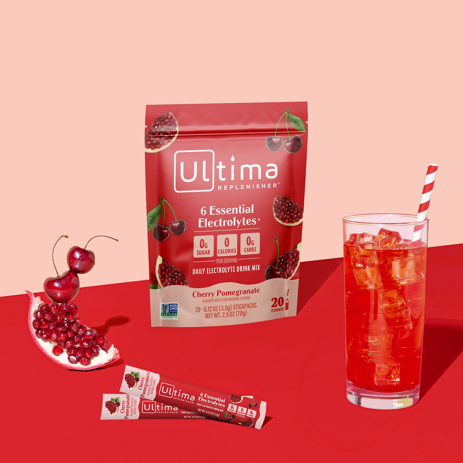 Ultima Replenisher Cherry Pomegranate electrolyte hydration powder pouch lifestyle with glass and fruit