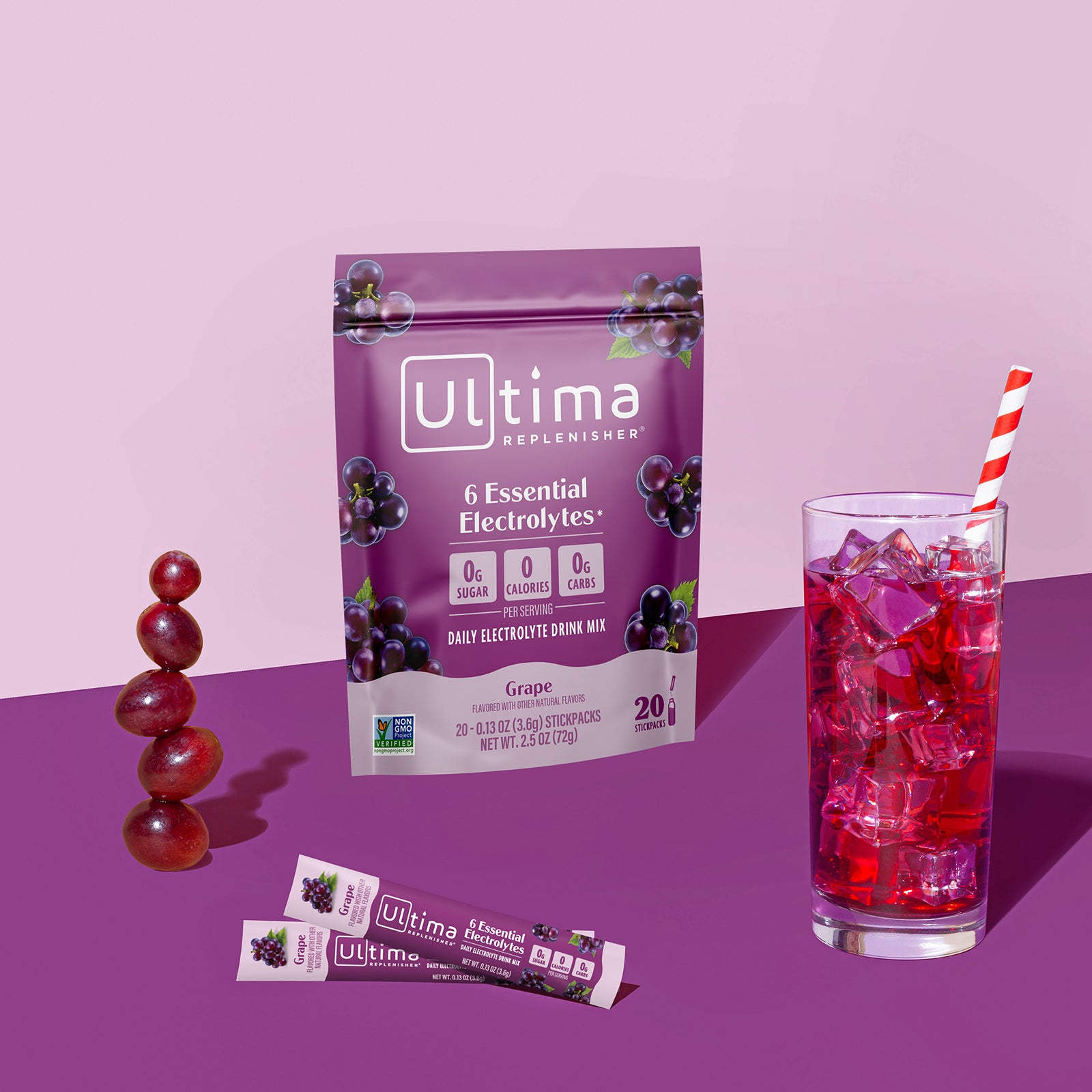 Ultima Replenisher Grape electrolyte hydration powder pouch lifestyle with glass and fruit