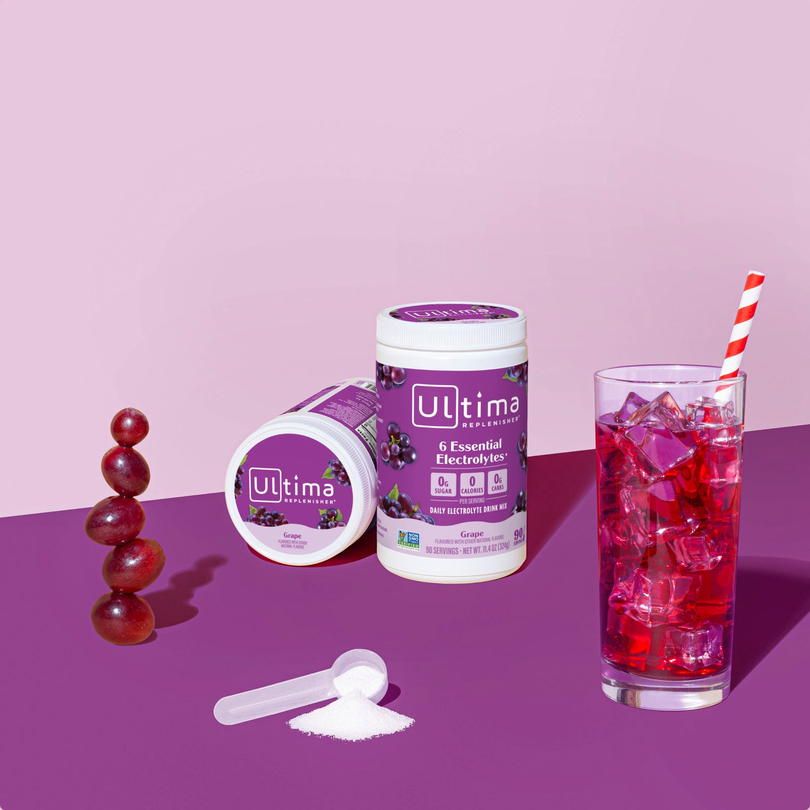 Ultima Replenisher Grape electrolyte hydration powder 90 serving canister lifestyle with glass and fruit